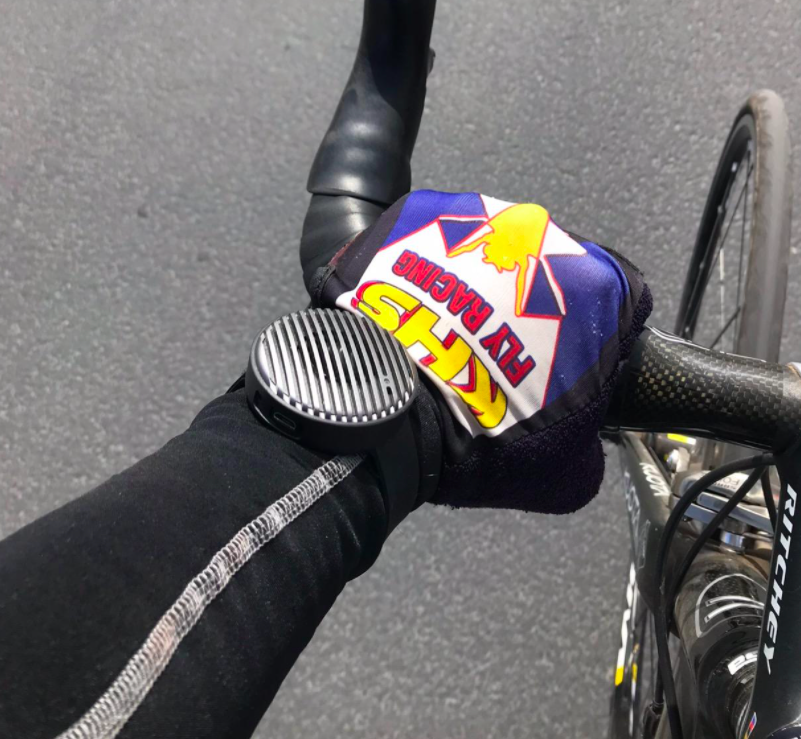 reviewer&#x27;s arm holding on to a bike handle bar with the watch-shaped speaker on their wrist