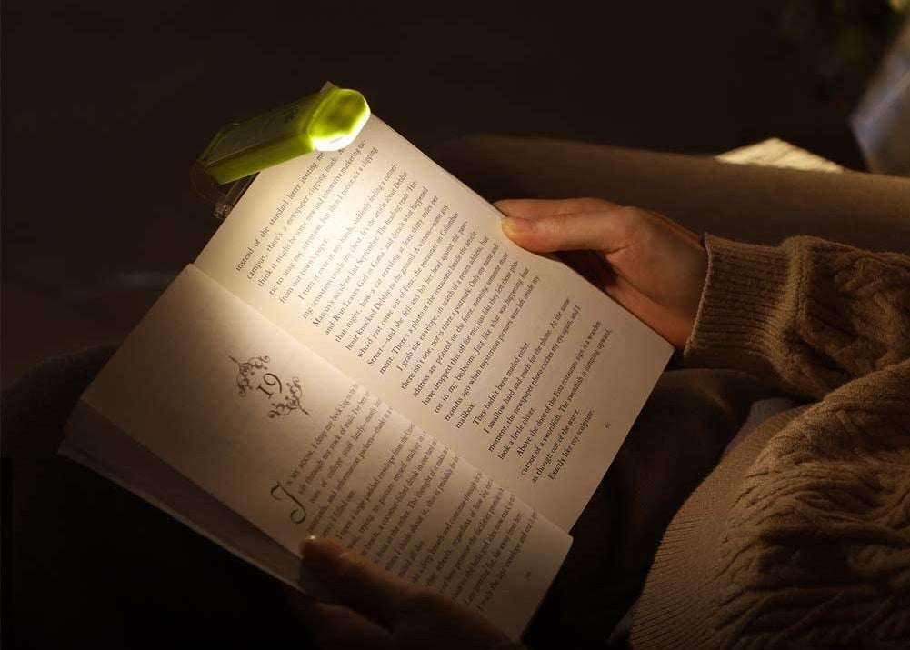Someone reading a book using the clip-on book light