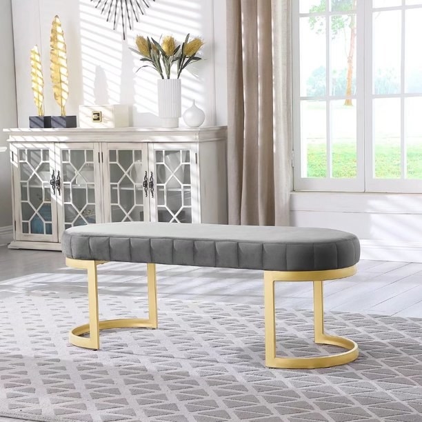 the gray bench with gold legs on a light gray carpet