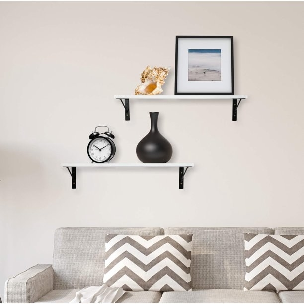 the wall shelves hanging with a clock, vase and picture frame on them