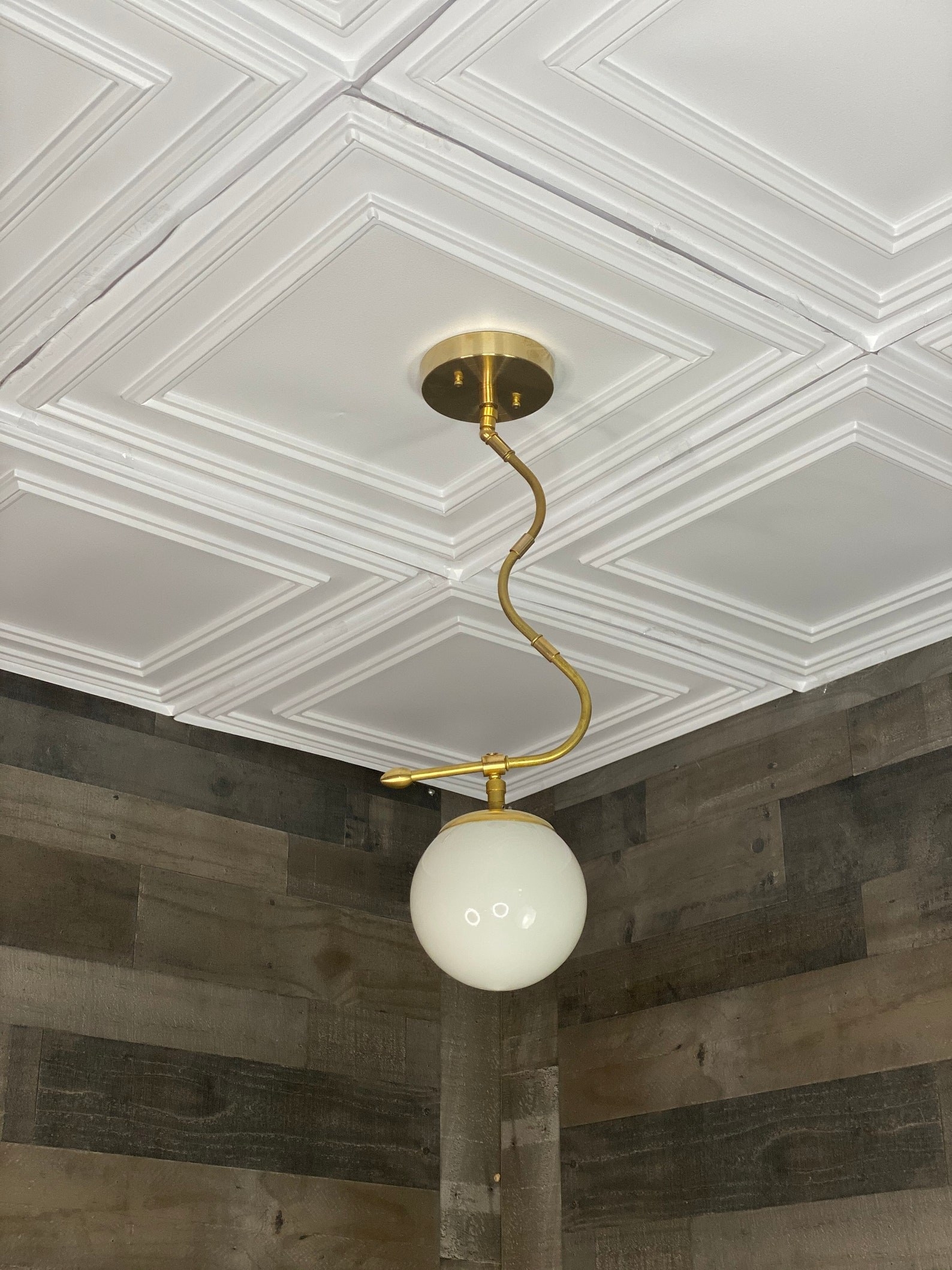 globe light bulb hanging from twisted gold tone pendant installed flat on the ceiling