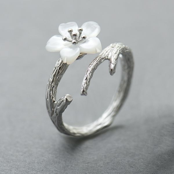 The silver ring with an open design and a white cherry blossom