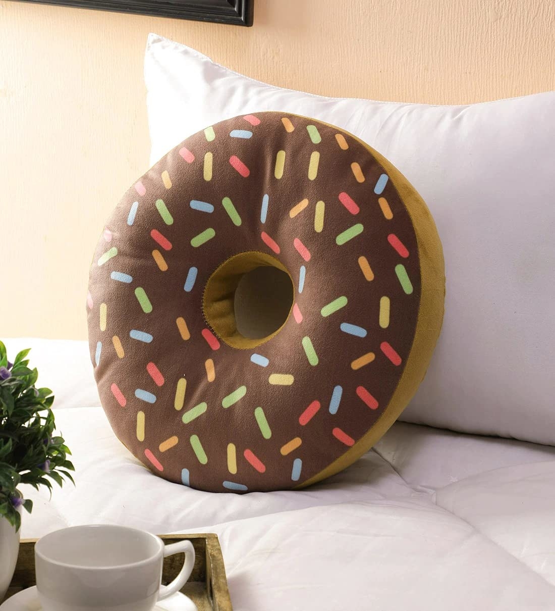 The pillow is designed to look like a chocolate frosted donut with sprinkles on top