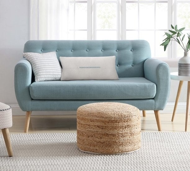 natural jute floor pouf next to a blue couch