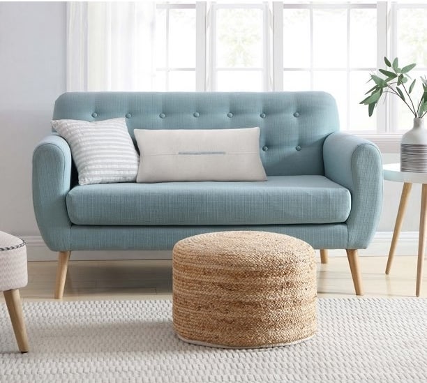 natural jute floor pouf next to a blue couch