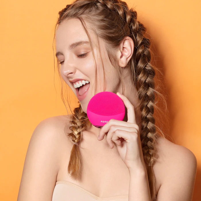 A person holding a Foreo Luna face brush up to their face