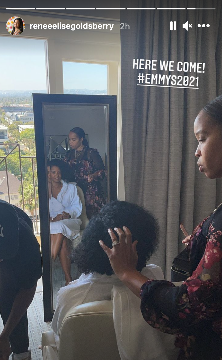 Renee Elise Goldsberry sits in a chair in front of a full length mirror getting her hair done