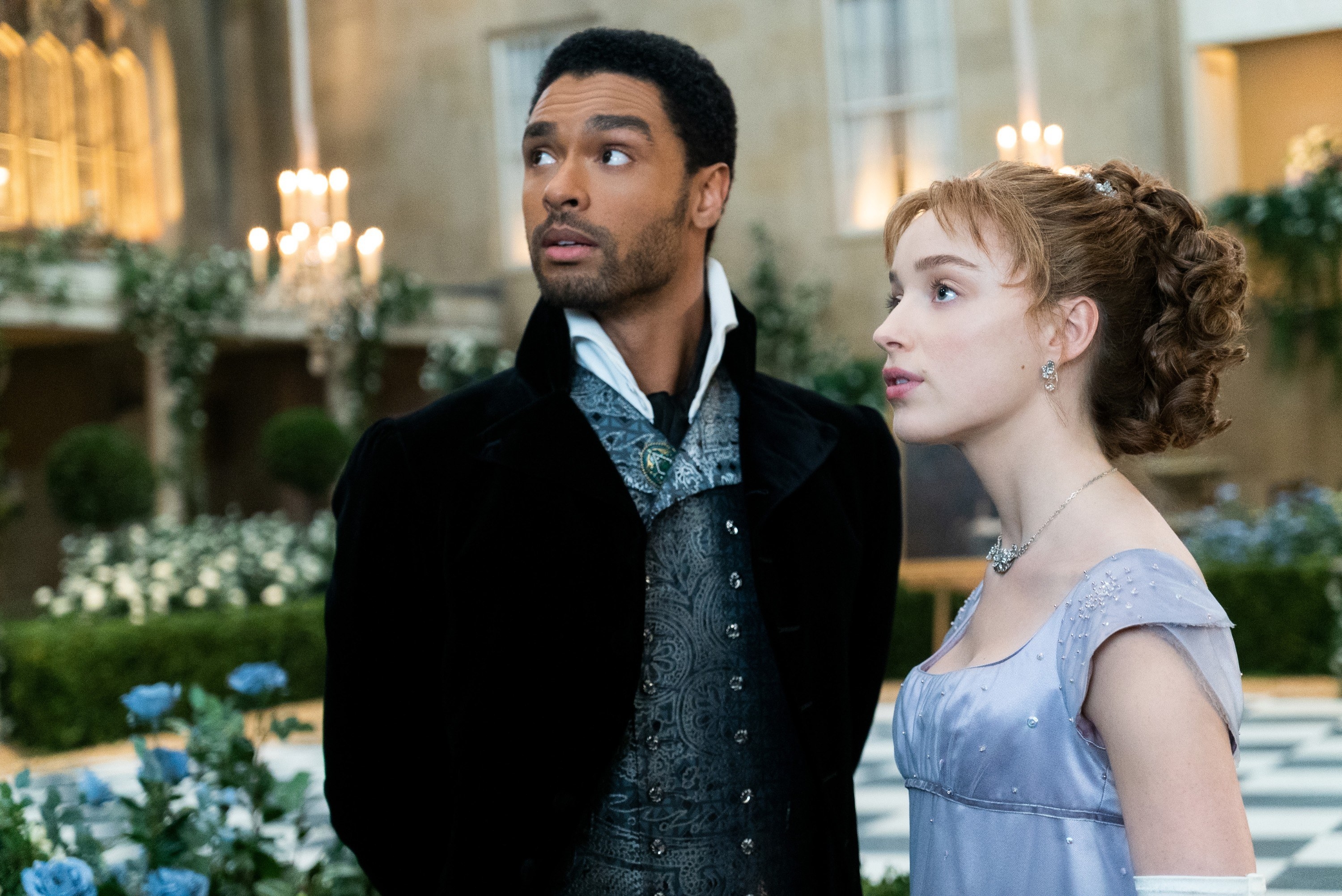 Regé-Jean Page and Phoebe Dynevor standing next to each at a ball in a scene from Bridgerton