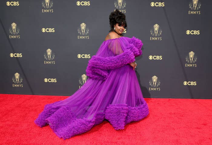 Nicole Byer on the red carpet in a large, fluffy purple gown