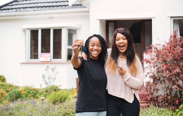 Two happy young women showing off the keys to a new house