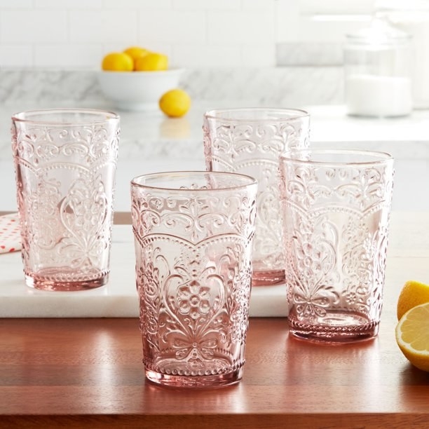 four rose colored glass tumblers on a table