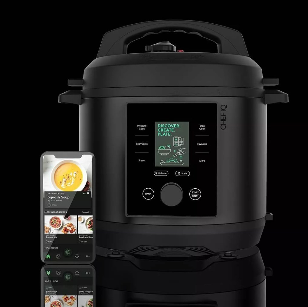 A black, wifi-controlled pressure cooker next to a phone displaying the associated app