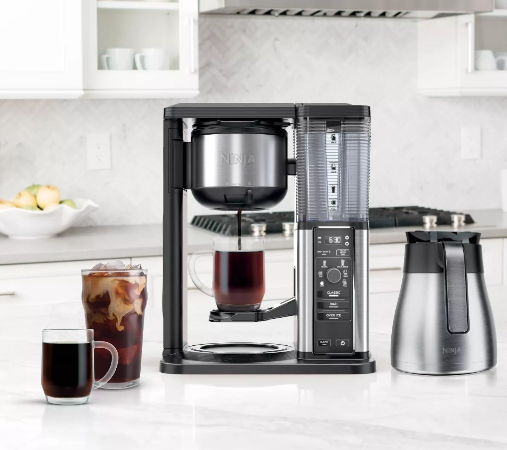 A black Ninja iced &amp;amp; hot coffee maker on a kitchen counter next to cups of iced coffee and hot coffee