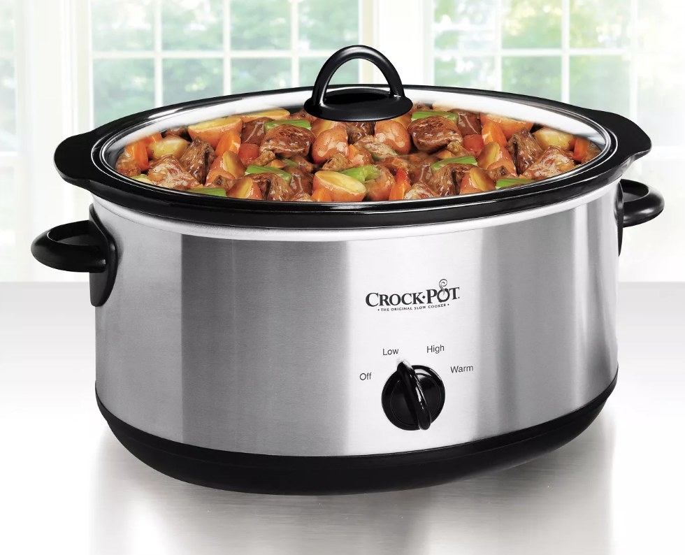 A black/silver, Crock-Pot filled with a beef stew on a kitchen counter