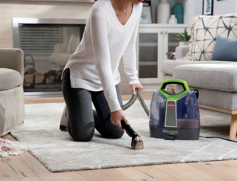 A model using a portable deep cleaner to remove a stain from a carpet