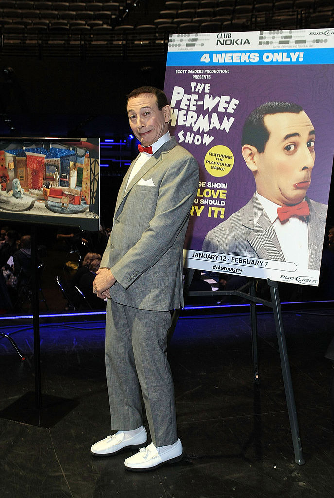 Pee-wee posing next to a poster advertising his show