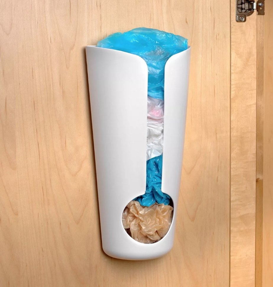 A white grocery bag holder mounted to the inside of a cabinet