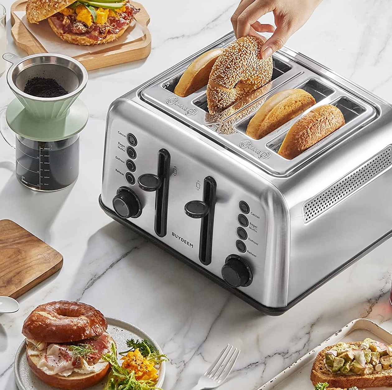 Someone inserting a bagel into a four-slice toaster