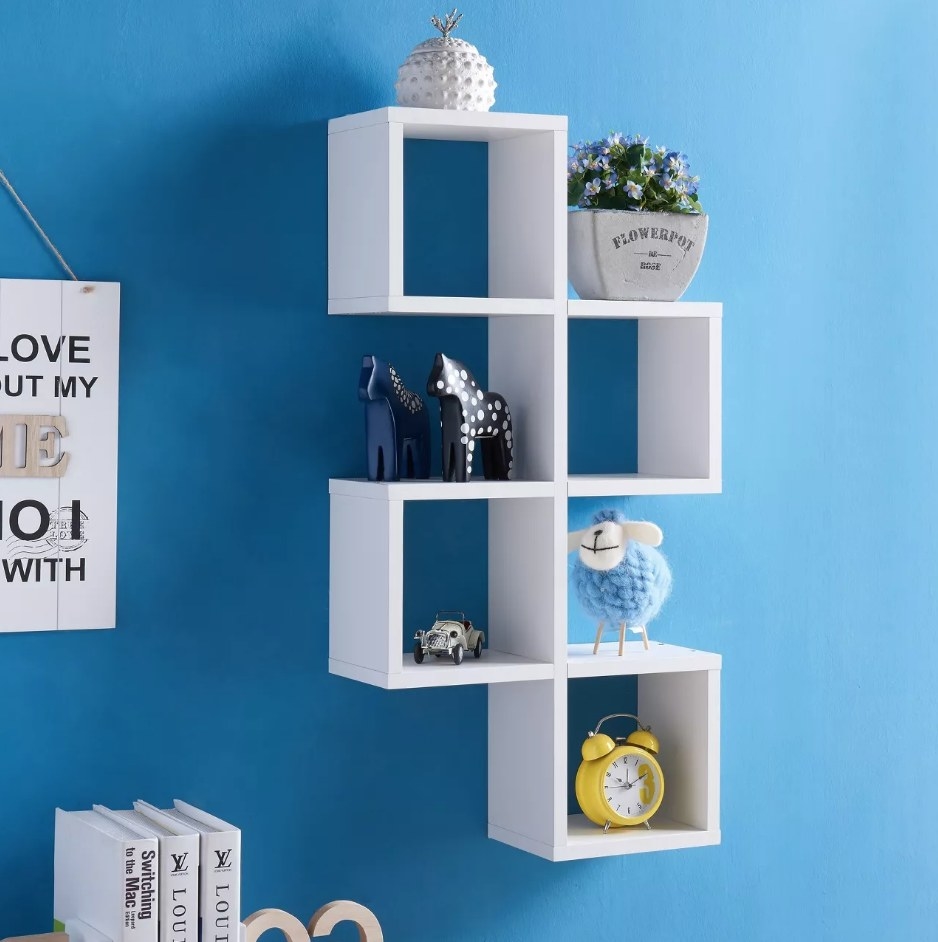 A white, geometric wall cube shelf with 8 shelves filled with decor