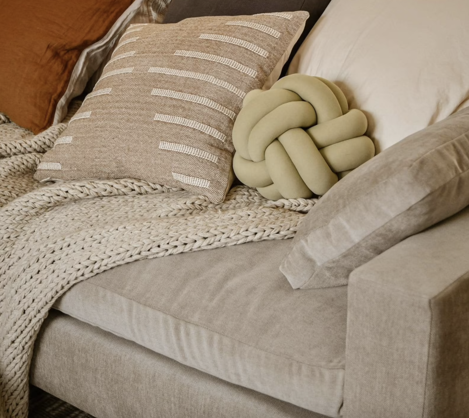 the sage green knot pillow on a linen couch