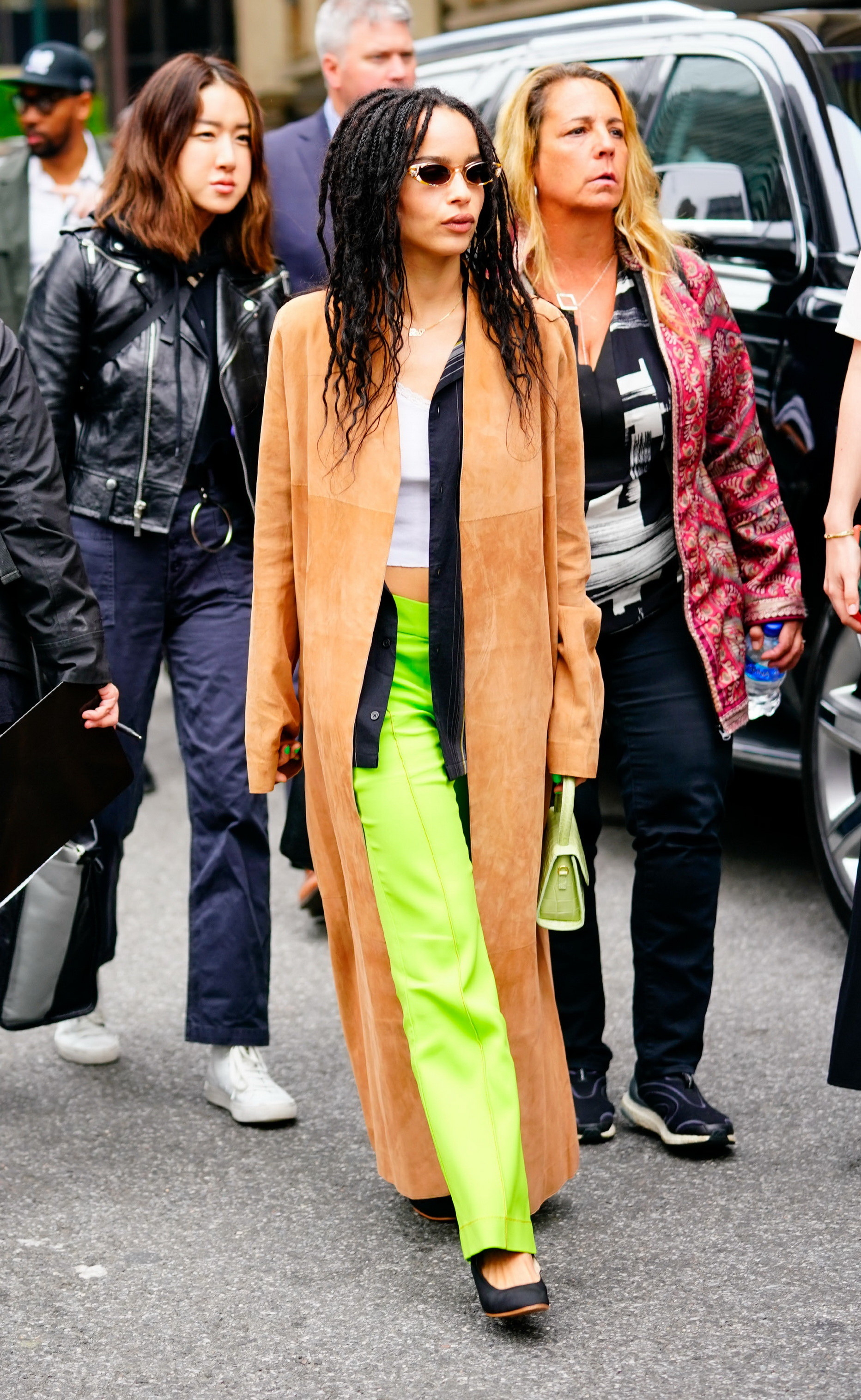 Zoe outside in bright pants, long suede coat, shades