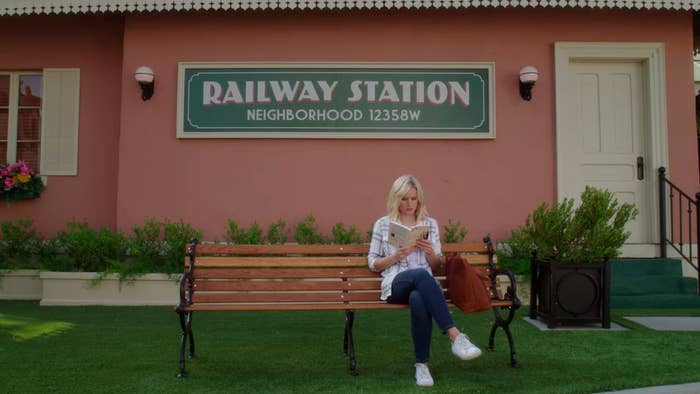 Eleanor sitting beneath a sing that says, Railway Station, neighborhood 12358W