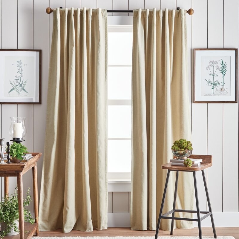 the pair of beige curtains hanging from a window