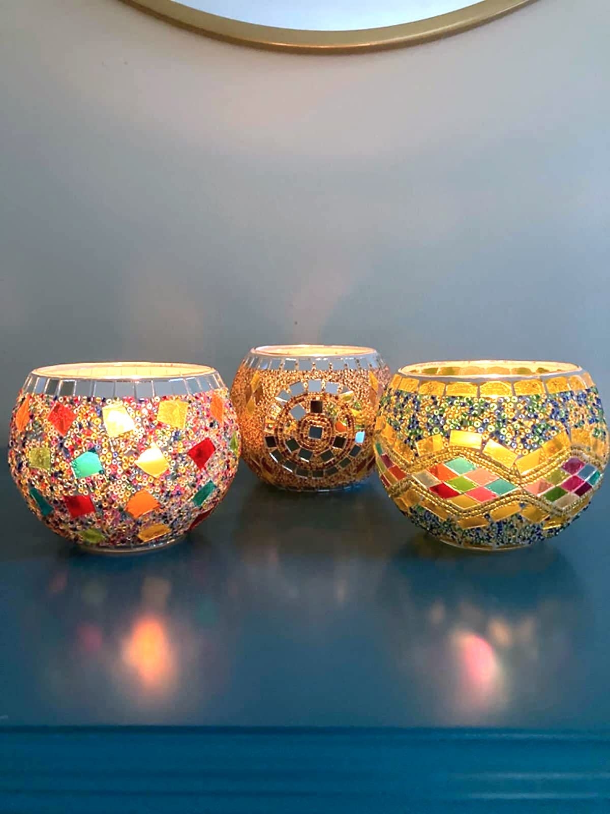 reviewer's three tealight holders with lit candles in them