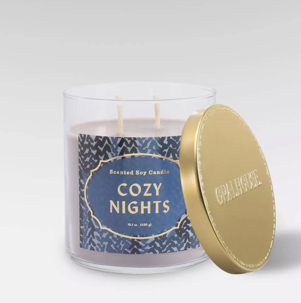 a light purple candle with a blue design on it and a label that says &quot;cozy nights&quot;