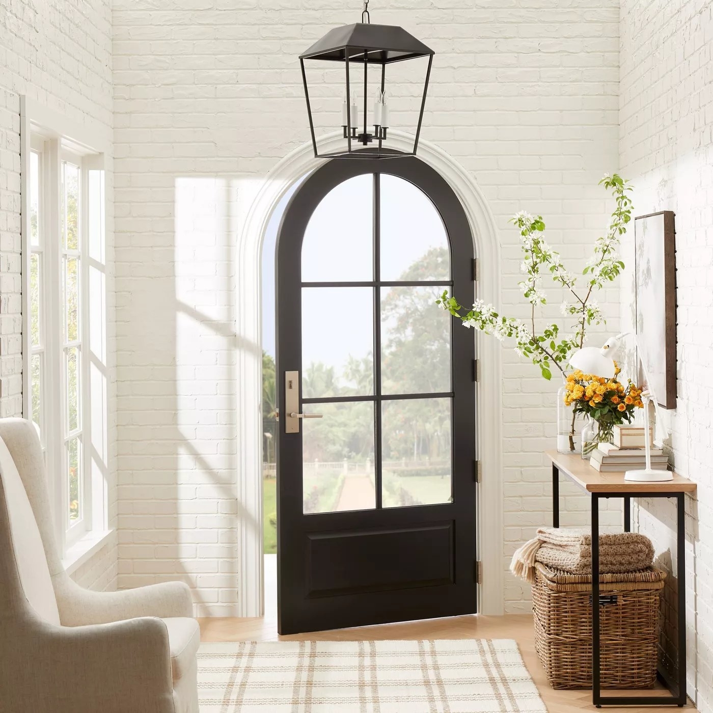The lantern pendant with a black frame and four candelabra bulbs hanging in an entryway