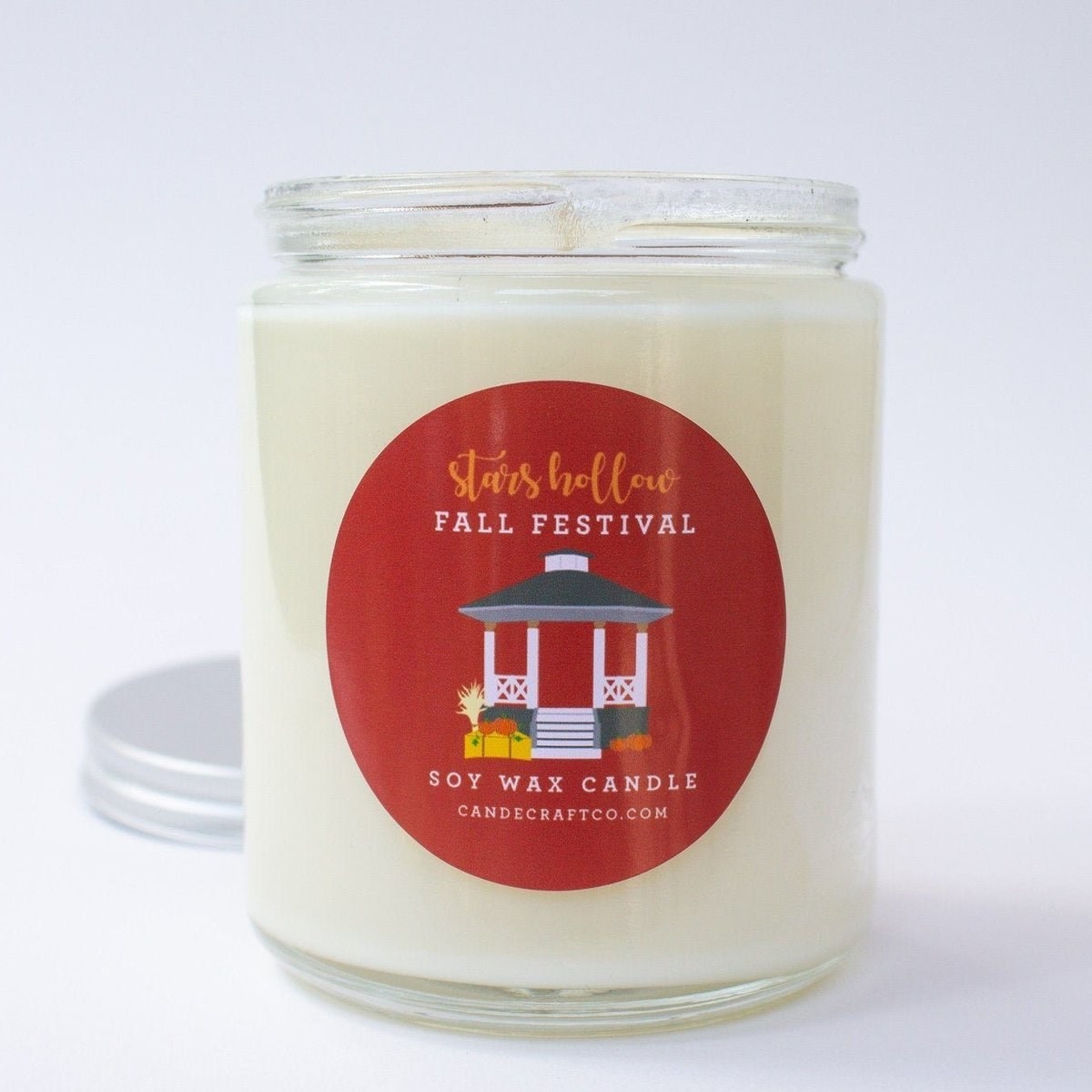 a white candle with the stars hollow gazebo on it in a red circle