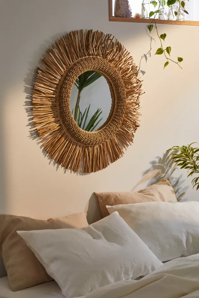A mirror on a wall above a bed