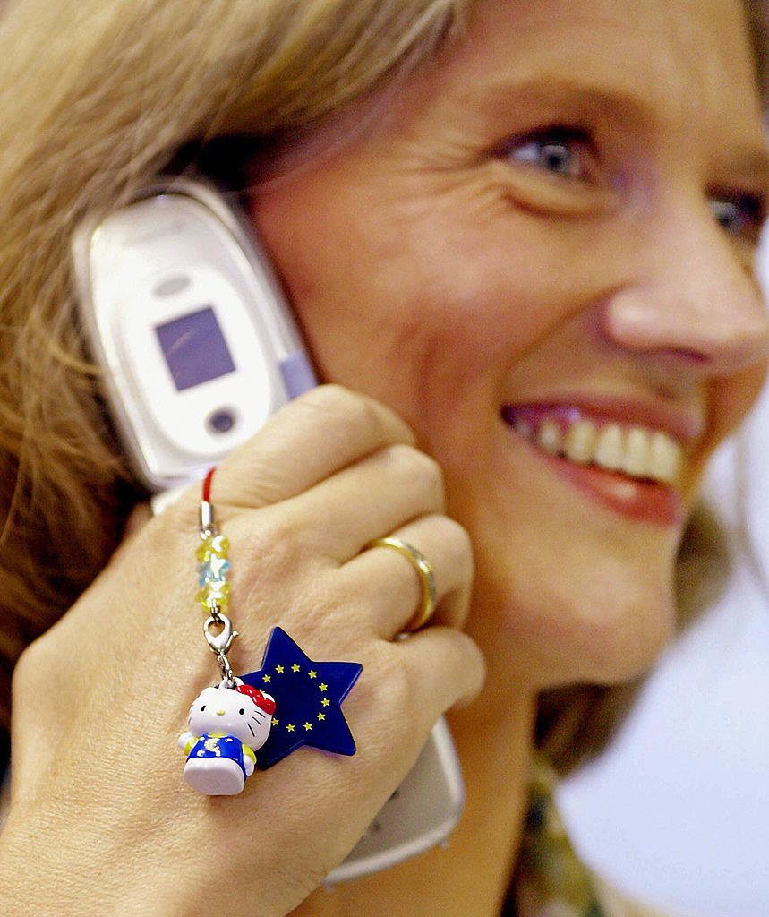 A woman talks on a phone that has two charms: hello kitty and a european union star