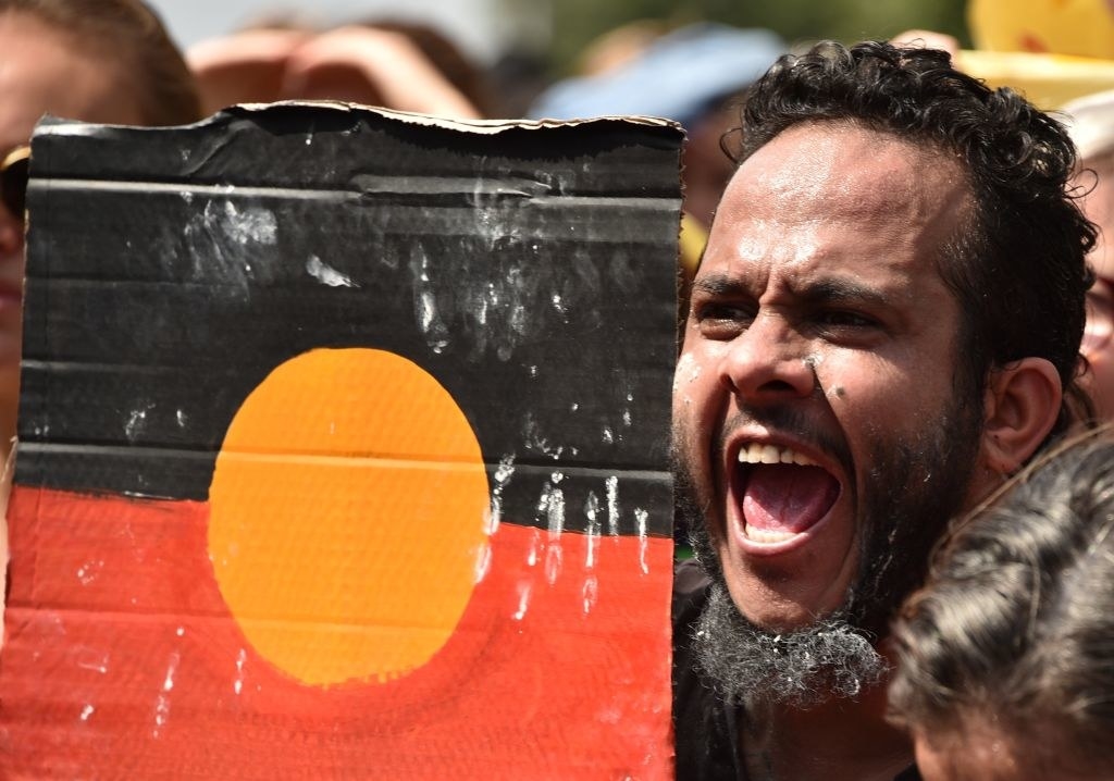 A protester holds up a design with the Aboriginal flag during an "Invasion Day" rally on Australia Day in Melbourne