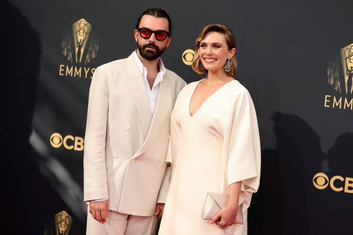 Elizabeth Olsen wears a deep v-neck light colored gown  and Robbie Arnett wears a light colored suit