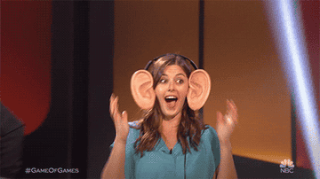 Gif of a women with a large grin and super large ear headphones
