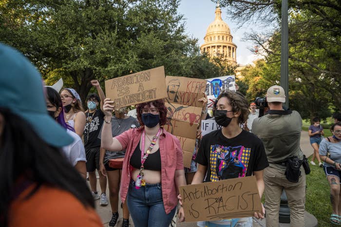 A group of women holding signs which say Abortion is a human right and Abortion is racist during a march against the abortion ban