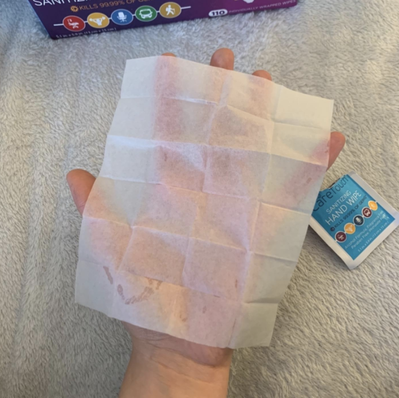 person with open hand sanitizing wipe larger than the palm of the hand