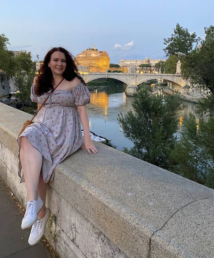 writer sitting on edge of bridge with Rome in the background