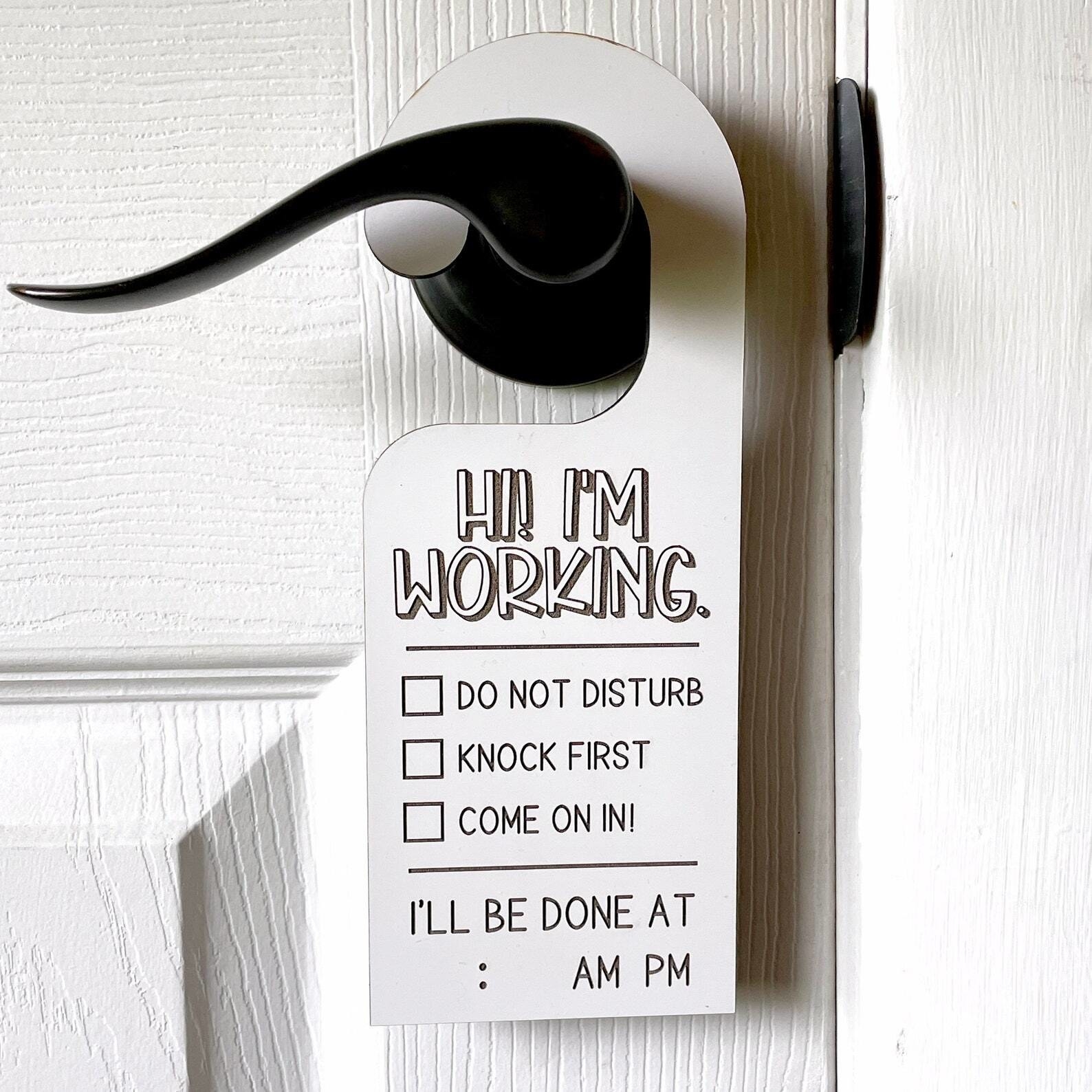 whiteboard sign hanging from doorknob that says hi i&#x27;m working with three checkbox options, do not disturb, knock first, come on in. it includes a spot to say when you&#x27;ll be done.