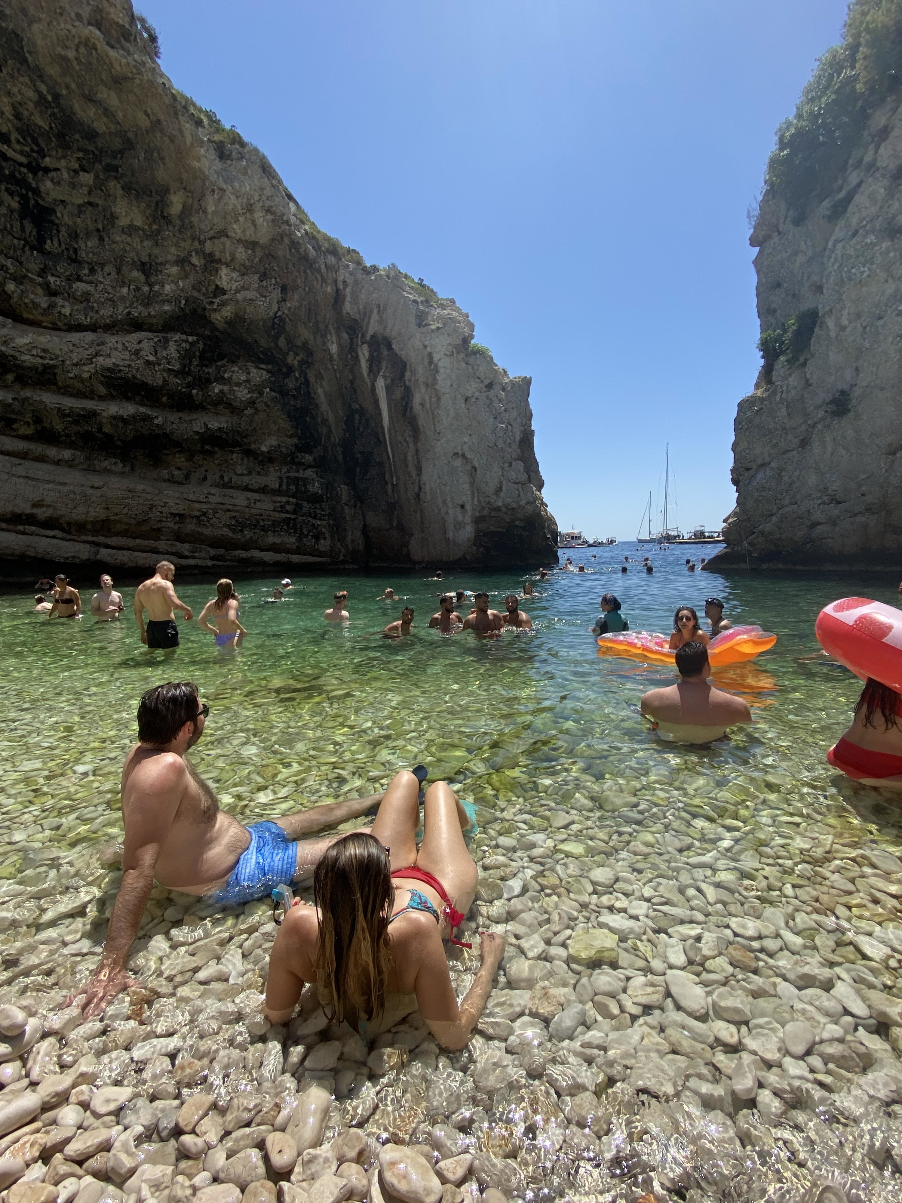 beach in Croatia with lots of people sitting or floating in the shallow water