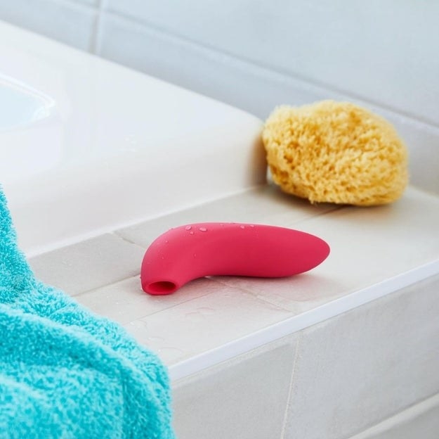 Pink suction vibrator on edge of bathtub