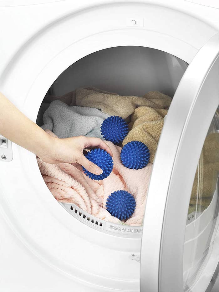 a model putting the blue balls in a dryer with laundry
