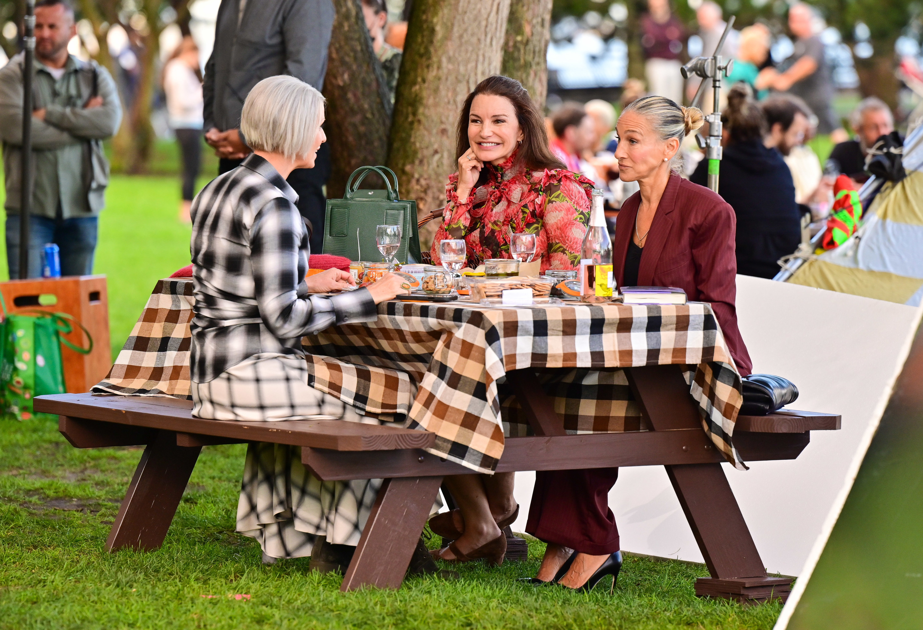 Cynthia Nixon, Kristin Davis, and Sarah Jessica Parker sitting at a table outdoors