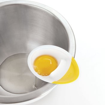the separator holding a yolk with whites in the bowl