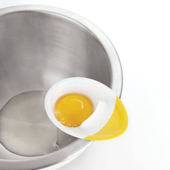 the separator holding a yolk with whites in the bowl