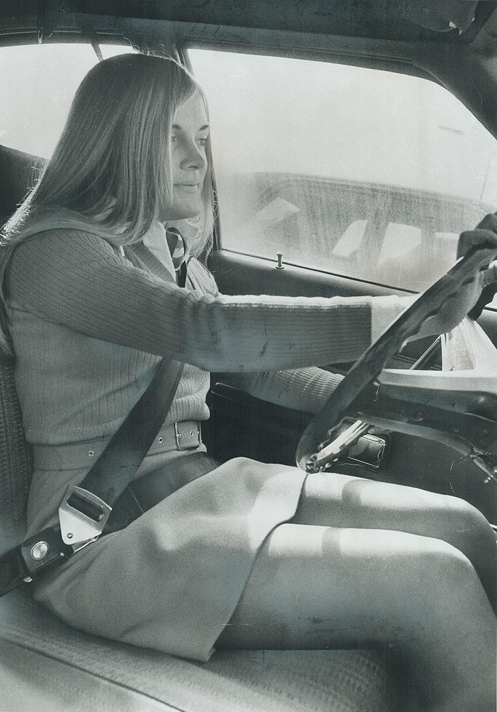 An old photo of a woman driving with her seatbelt on