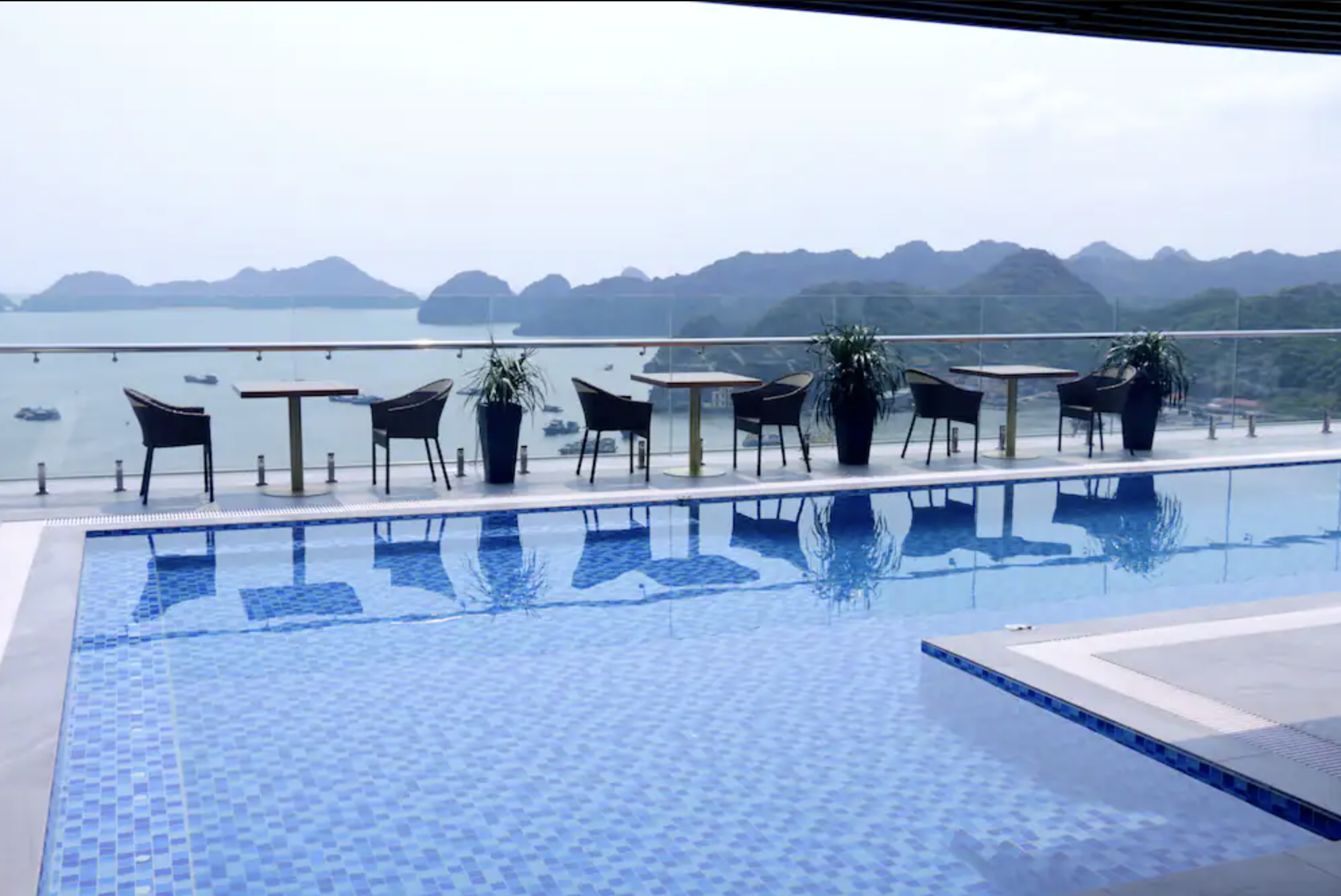 Large rooftop pool with seating that overlooks the karsts of Halong Bay