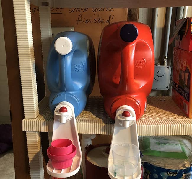 two bulk detergent bottles with the cup holders attached to the spouts