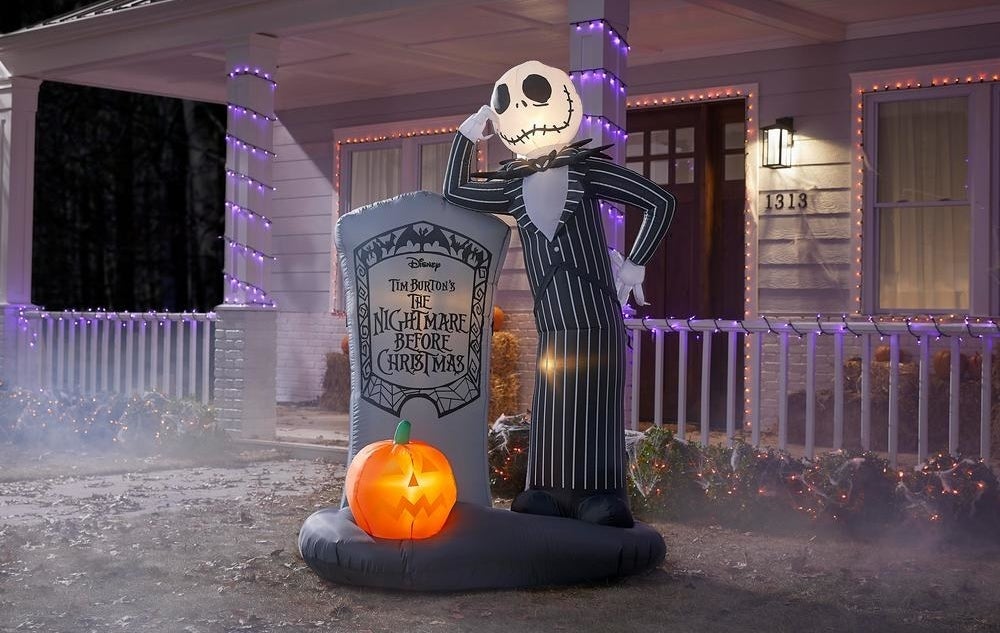 a blow up of jack skellington leaning next to a tomb stone